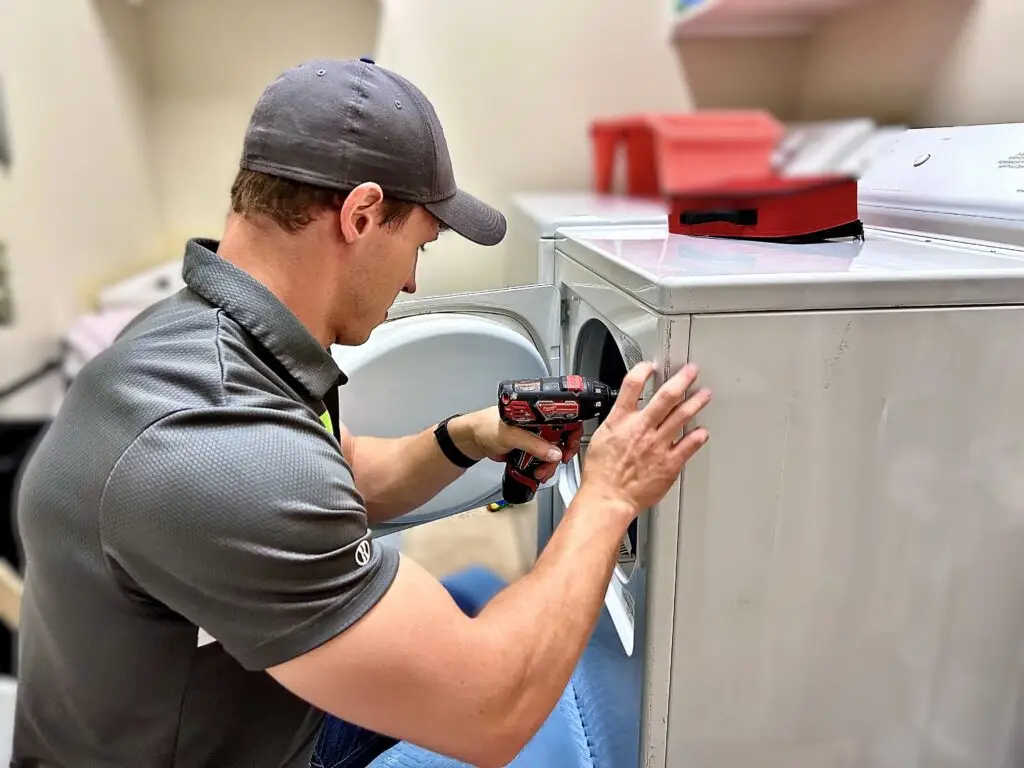Adam Bigelow the CEO of BA Appliance Repair Service, Repairing a dryer in a laundry room.