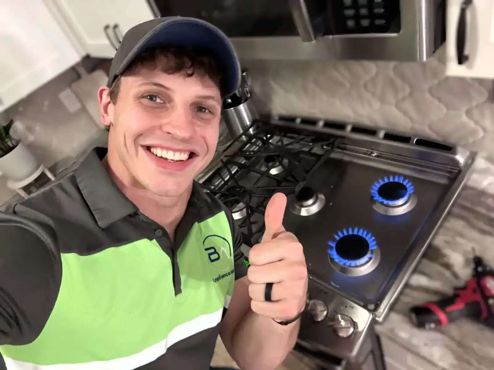 BA Appliance Repair technician giving a thumbs-up beside a lit gas cooktop